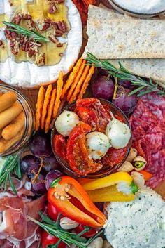 an assortment of food on a platter with crackers, cheeses and vegetables