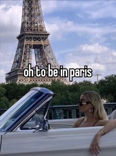 a woman leaning on the back of a car in front of the eiffel tower