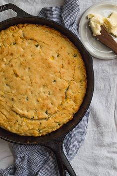 a skillet with some food in it on a table next to a plate and spoon