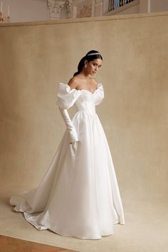 a woman in a white wedding dress posing for the camera with her hands on her hips