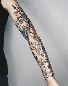 a woman's arm with tattoos on it and flowers in the middle of her arm