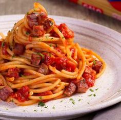 spaghetti with sausage and tomato sauce on a white plate