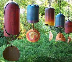 several colorful wind chimes hanging from chains in a garden