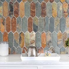 a kitchen counter with a white sink and tiled backsplash in the backround