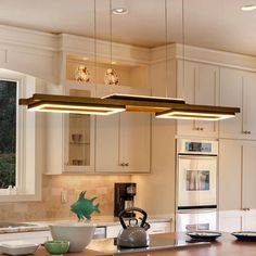 a kitchen with a tea kettle on the counter and lights hanging from the ceiling above it