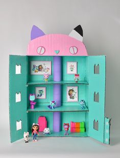 an open cardboard doll house with dolls and toys in the inside, on a gray background