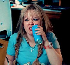 a woman sitting at a table drinking from a blue cup