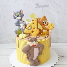 a birthday cake decorated with cartoon characters and the number four on it's top