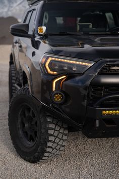 the front end of a black truck with lights on it's grille and tires