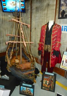 an old fashioned pirate ship on display in a museum case with other items around it