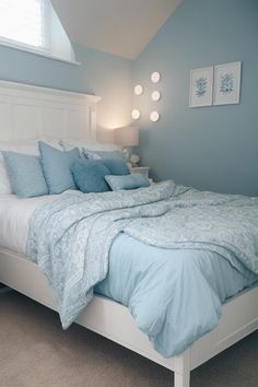 a white bed with blue sheets and pillows