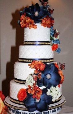 a three tiered wedding cake with blue and orange flowers