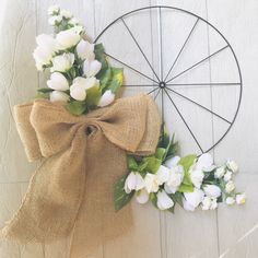 a wreath with white flowers tied to it next to a burlock on the wall