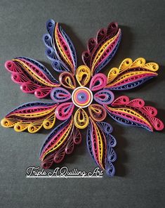 an origami flower made out of colored paper on a black surface with the words type of quilling art written below it