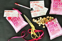 three bags of popcorn sitting on top of a table next to scissors and some paper