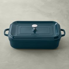 a blue casserole dish with a lid and handle on a gray table top