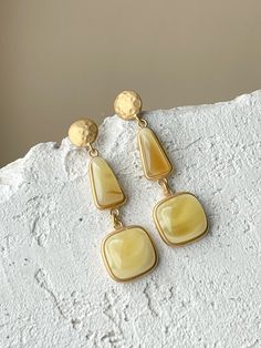 These striking gold-plated teardrop earrings are embellished with mate amber for a touch of elegant shine. Their length of 1.97 inches elegantly complements any ensemble. Wear them for a subtle statement of style. Luxury Yellow Dangle Earrings, Luxury Yellow Teardrop Earrings, Elegant Drop Earrings With Plating, Elegant Gold Long Drop Linear Earrings, Chic Metal Teardrop Earrings For Formal Occasions, Elegant Gold Long Drop Chandelier Earrings, Elegant Gold Plated Long Drop Earrings, Plated Chandelier Drop Earrings, Elegant Gold-tone Dangle Chandelier Earrings