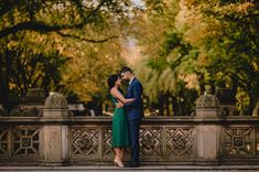 a man and woman standing next to each other in front of trees