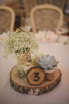 the table is set up with flowers and succulents in vases on wood slices