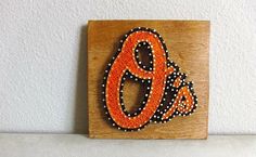 an orange and black beaded amp sign on a wooden block with the letter'o '