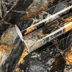 a marbled surface with gold and black accents, including two knives on top of each other