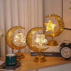 two golden moon and star lights on top of a table next to a coffee cup