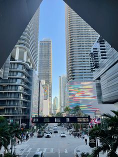 a city street filled with lots of tall buildings next to palm trees and parked cars