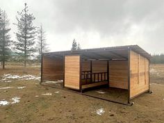 a small wooden building sitting on top of a grass covered field with trees in the background