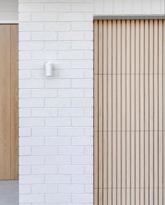 a white brick wall with two doors and a wooden door handle on the left side