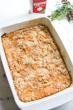 a casserole in a white dish next to a bottle of eggnox