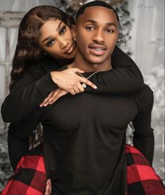 a young man and woman embracing each other in front of a christmas tree with lights