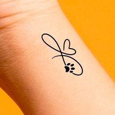 a small tattoo on the wrist of a person with a heart and a bug in it