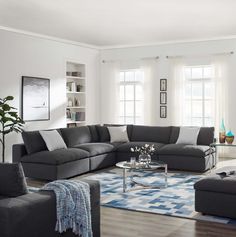 a living room with grey couches and blue rugs on the hardwood flooring