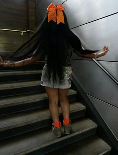 a woman with long black hair standing on some stairs