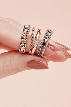 a woman's hand holding three rings on top of her finger