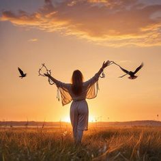 a woman standing in a field with two birds flying over her head and arms outstretched