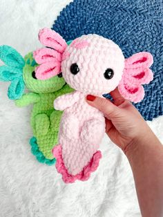 a hand holding a small crocheted stuffed animal next to two smaller knitted toys