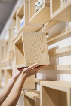 a person holding a wooden object in front of shelving unit with shelves on both sides