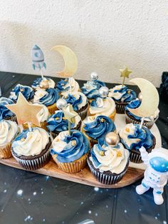 cupcakes with blue icing and white frosting are arranged on a wooden tray