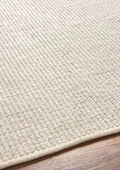 a close up view of a white rug on a wooden floor with a wood table in the background