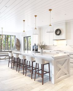 a large kitchen with white cabinets and counter tops, along with bar stools in front of the island