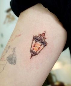 a small tattoo on the back of a woman's arm that has an orange diamond in it