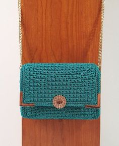 a green crocheted purse sitting on top of a wooden table next to a white wall