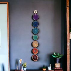 a room with a table, potted plant and vases hanging on the wall