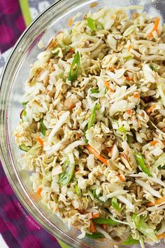 a bowl filled with rice and vegetables on top of a colorful table cloth next to a fork