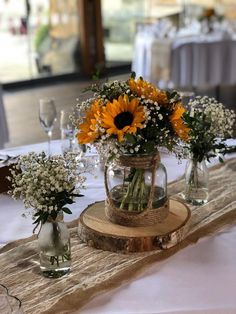 sunflowers and baby's breath in mason jars on a table at a wedding reception