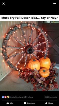 some pumpkins are sitting in front of an old wagon wheel with lights on it