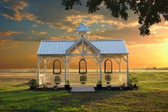 a small white house sitting on top of a lush green field