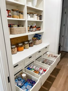 an organized pantry with white cabinets and open bins filled with food, snacks or condiments