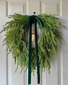 a christmas wreath hanging on a door with a green ribbon and bells attached to it